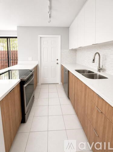 A kitchen with white cabinets and a white door.