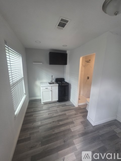 A kitchen area with a sink, a fridge, and a TV mounted on the wall.