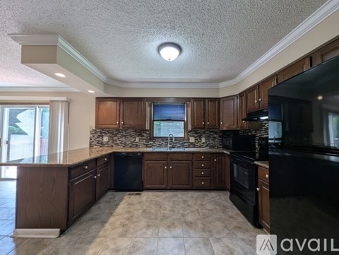 A kitchen with brown cabinets and black appliances.