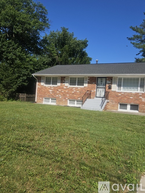 A house with a grey roof and a brick exterior is surrounded by a grassy lawn.