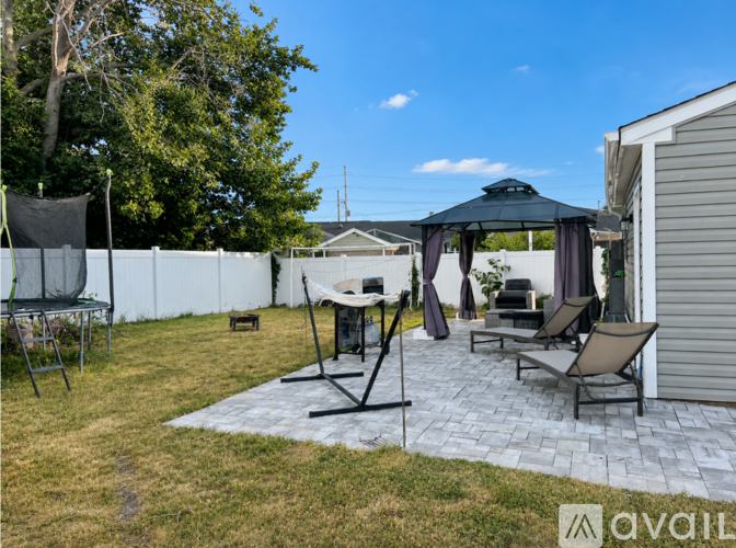 A backyard with a patio, chairs, and a gazebo.