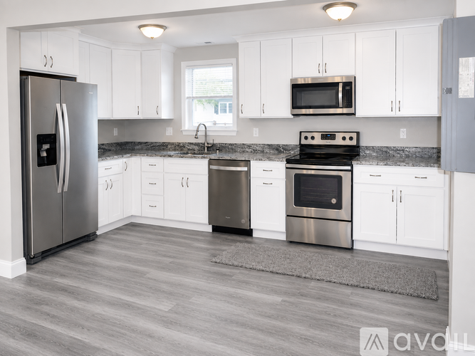 A kitchen with white cabinets and a grey floor.