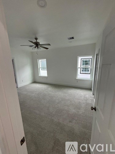 A room with a ceiling fan and two windows.