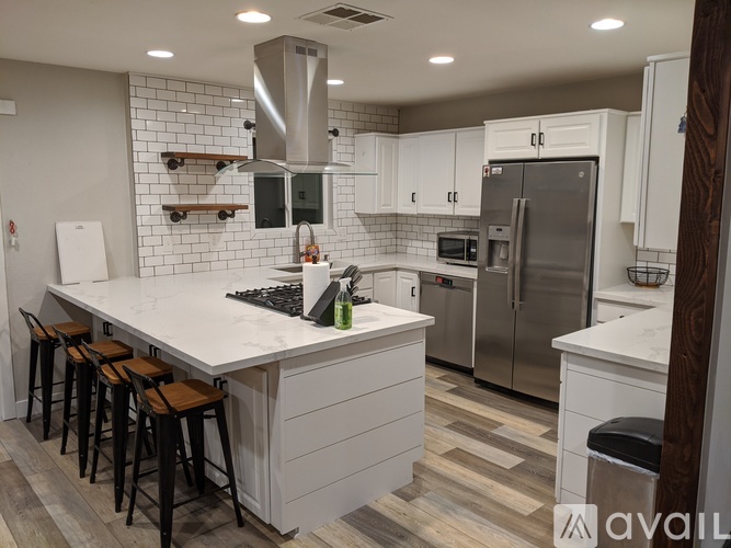 A modern kitchen with white cabinets and a marble countertop.