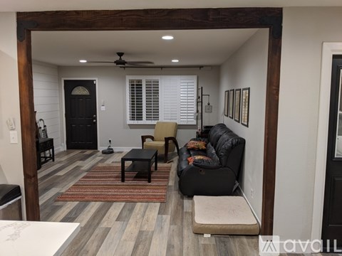 A living room with a black couch and a wooden floor.