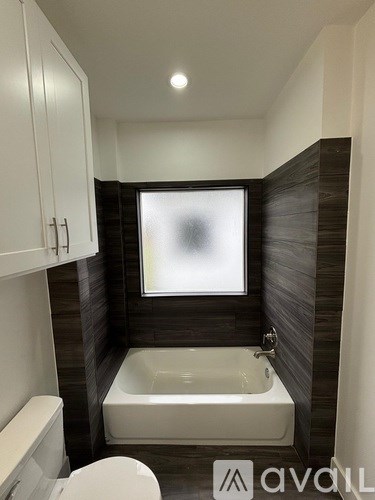 A bathroom with a white toilet, a white bathtub, and a window.