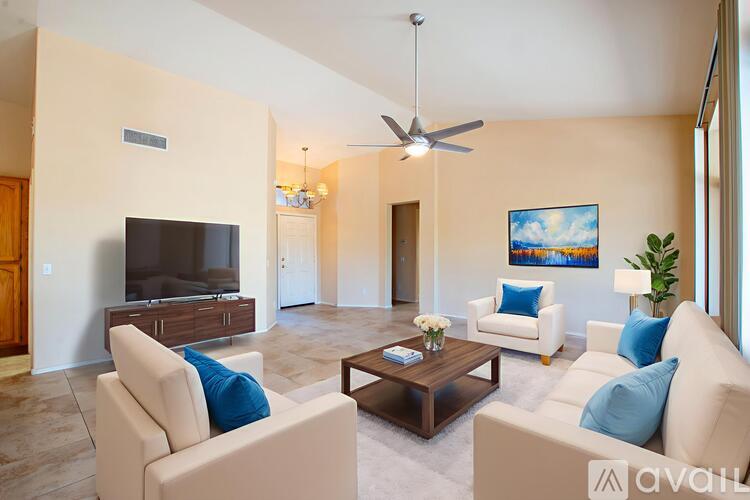 A living room with a television, two chairs, a coffee table, and a painting on the wall.