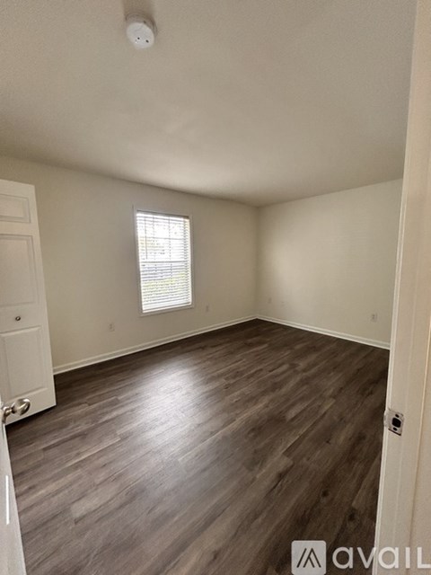 A room with wooden flooring and a window with blinds.