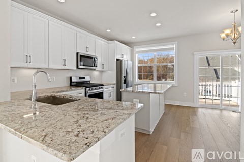 A kitchen with white cabinets and a marble countertop.