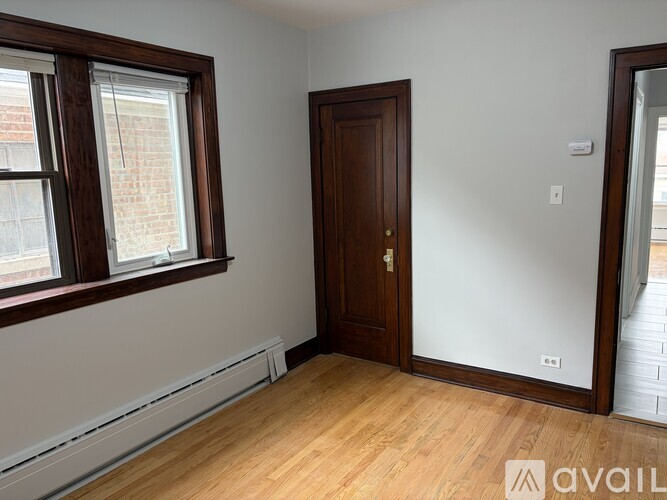 A room with a wooden door and a window with a view of a brick building outside.
