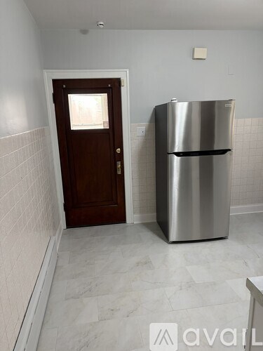 A kitchen with a stainless steel refrigerator and a wooden door.