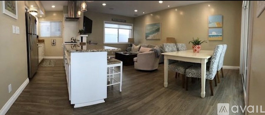 A kitchen with a white refrigerator and a dining table with chairs.