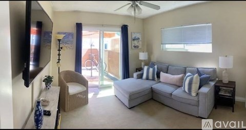 A living room with a grey couch and a ceiling fan.