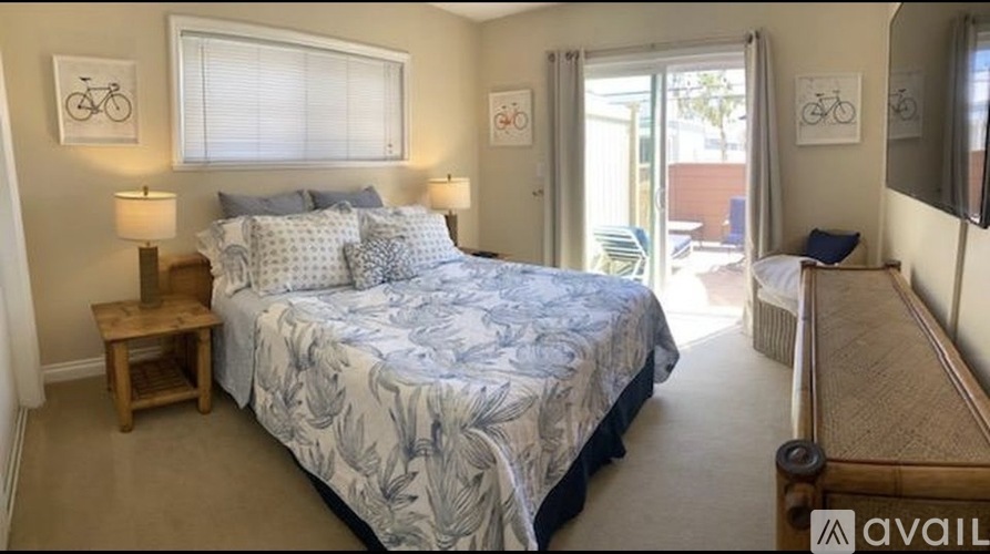 A bedroom with a large bed and a window with blinds.