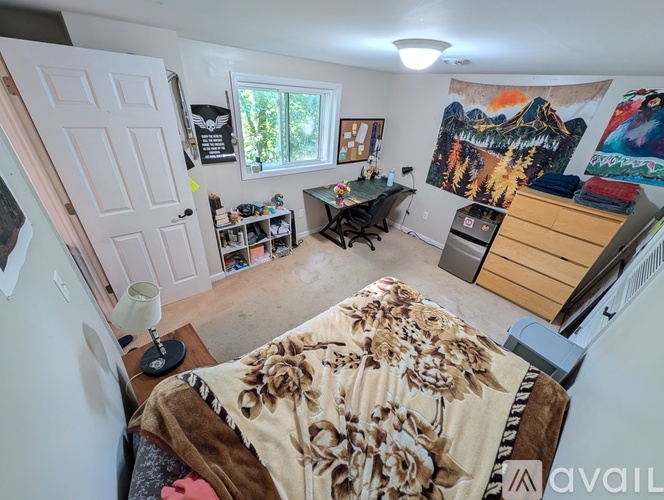A bedroom with a bed in the center and a painting on the wall.