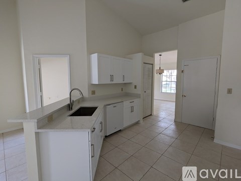 A kitchen with white cabinets and a marble countertop.