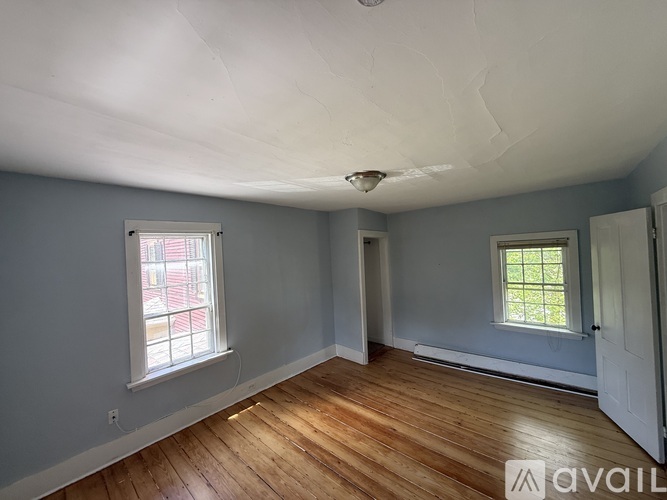 A room with wooden floors and two windows.