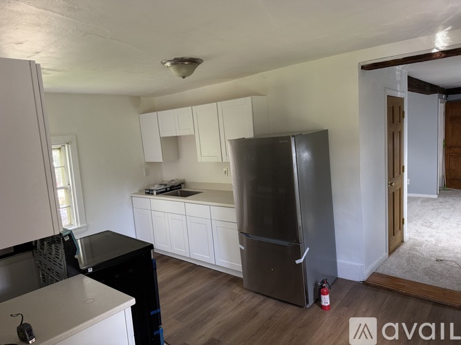 A kitchen with a black fridge and white cabinets.