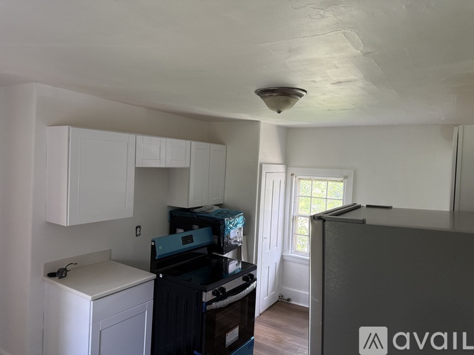 A kitchen with white cabinets and a black fridge.