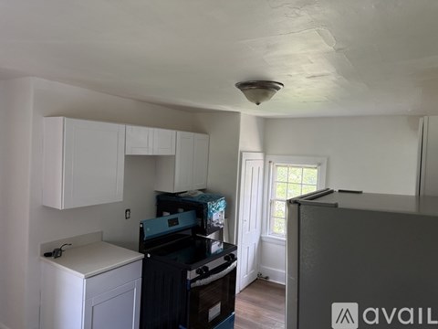 A kitchen with white cabinets and a black fridge.
