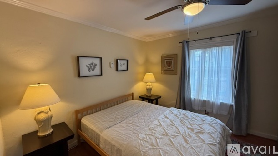 A bedroom with a bed, two lamps, and pictures on the wall.