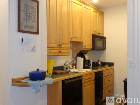 A kitchen with wooden cabinets and a blue pot on the counter.