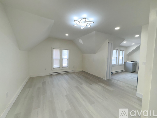 A spacious room with light wood flooring and a large window.