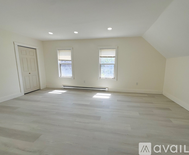 A spacious room with a wooden floor and two windows.
