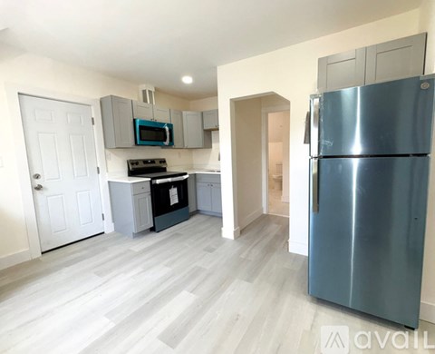 A kitchen with a blue refrigerator and white walls.