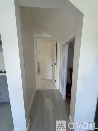 A hallway with a white wall and a grey floor.