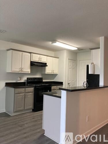 A kitchen with white cabinets and a black countertop.