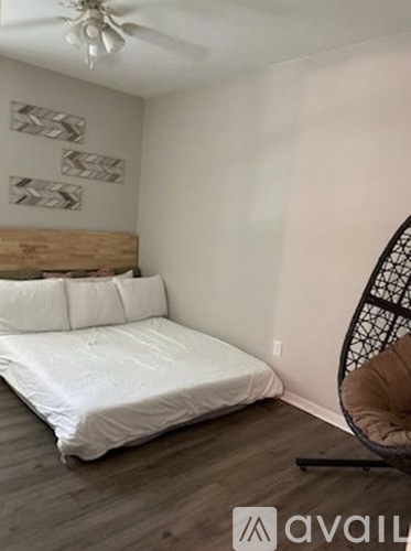 A bedroom with a bed, chair, and a ceiling fan.