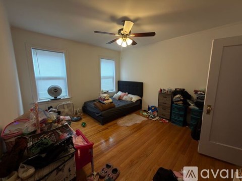 A messy bedroom with a bed, dresser, and a ceiling fan.