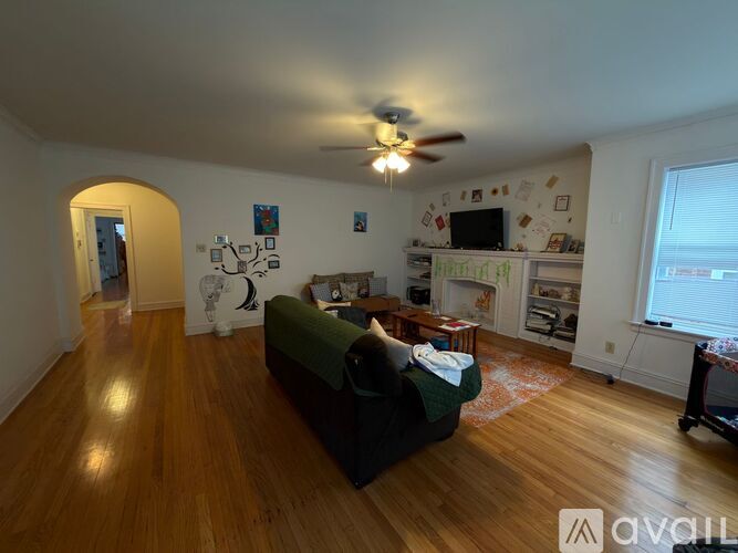 A living room with a green couch and a ceiling fan.