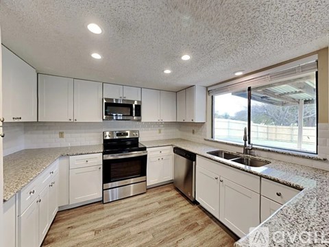 A kitchen with white cabinets and a granite countertop.