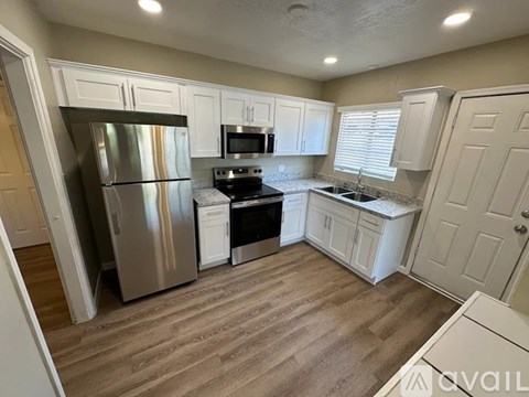 A kitchen with white cabinets and a stainless steel refrigerator.