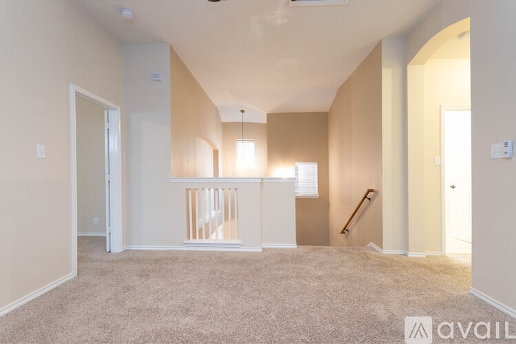 A spacious room with a carpeted floor and a staircase in the background.