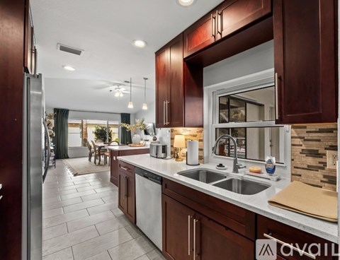 A kitchen with brown cabinets and a stone backsplash.