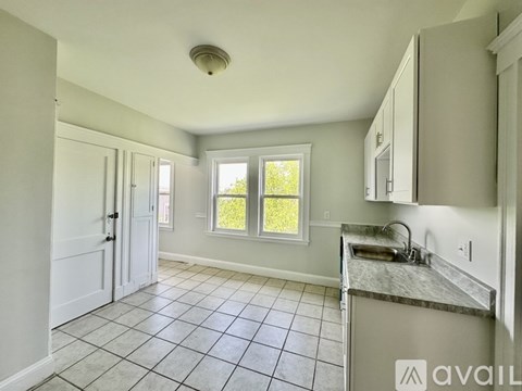 A kitchen with white cabinets and a marble countertop.
