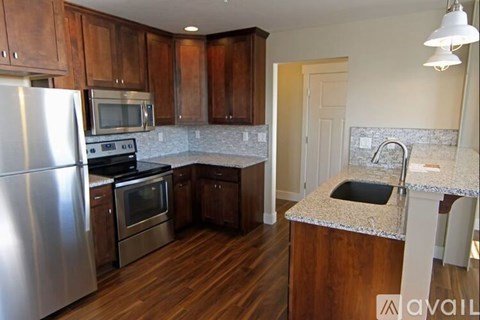 A kitchen with wooden cabinets and a stainless steel refrigerator.