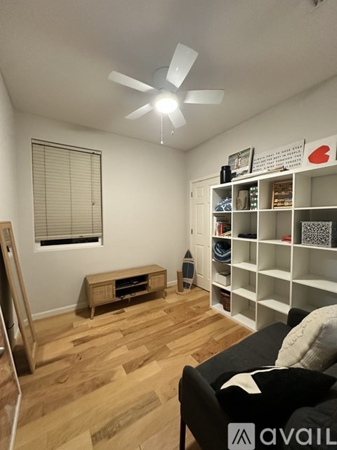 A living room with a black couch and a wooden floor.