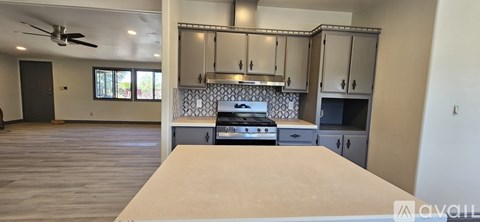 A kitchen with a stove top oven and a fan.