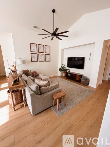 A living room with a grey couch and a ceiling fan.