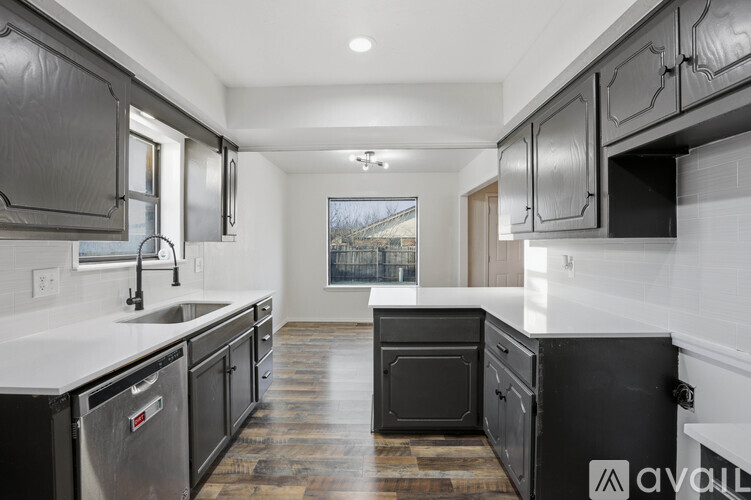 A modern kitchen with dark cabinets and a wooden floor.