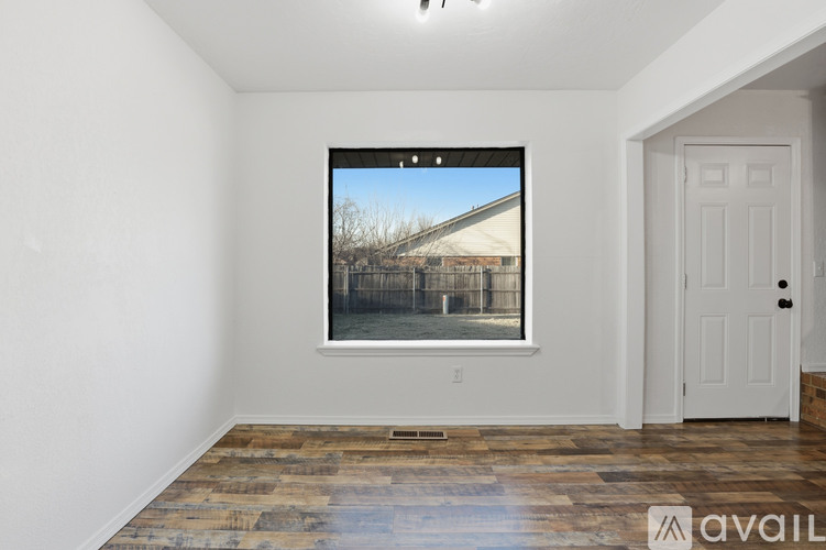 A room with a wooden floor and a large window showing a view of a building.