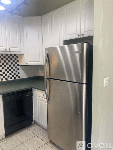 A stainless steel refrigerator in a kitchen with white cabinets.