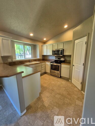 A kitchen with white cabinets and a brown countertop.