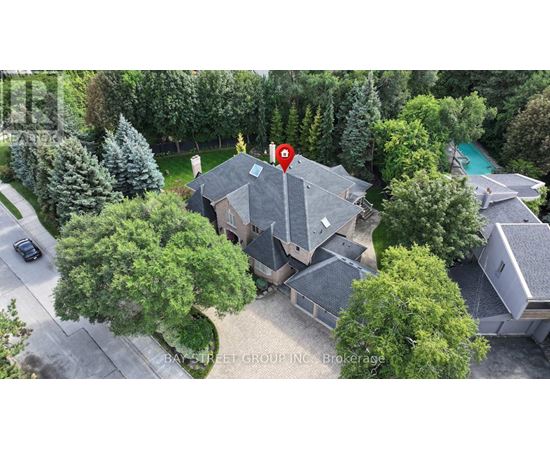 A house with a red pin on it is surrounded by trees and a pool.