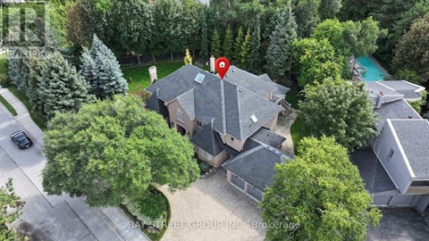 A house with a red pin on it is surrounded by trees and a pool.
