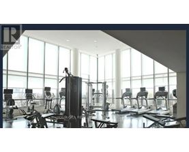 A gym with a row of treadmills and a row of stationary bikes.